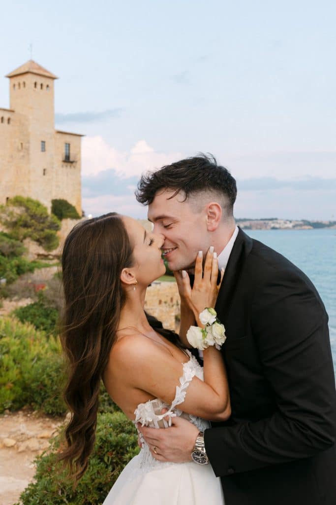 Boda en el castell de Tamarit. Beso de los novios frente al mar y al Castell de Tamarit al atardecer